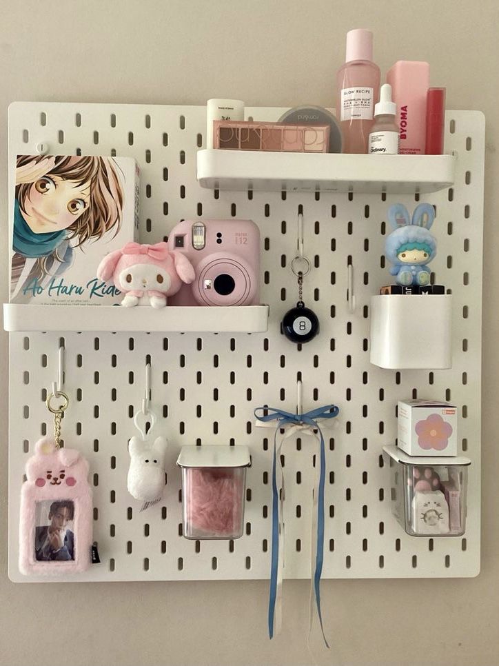 Organized wall pegboard with cute decor, books, pink camera, and storage containers for an aesthetic room setup.