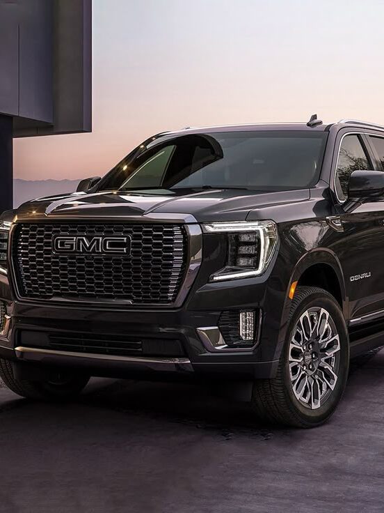 Black GMC Denali SUV parked at sunset, front view showcasing elegant design and modern features.