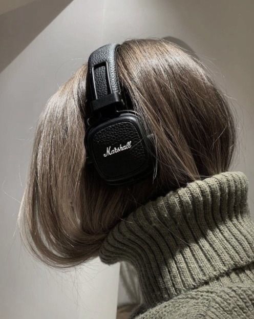 Person with headphones and a green sweater, showcasing Marshall headphones and modern style.