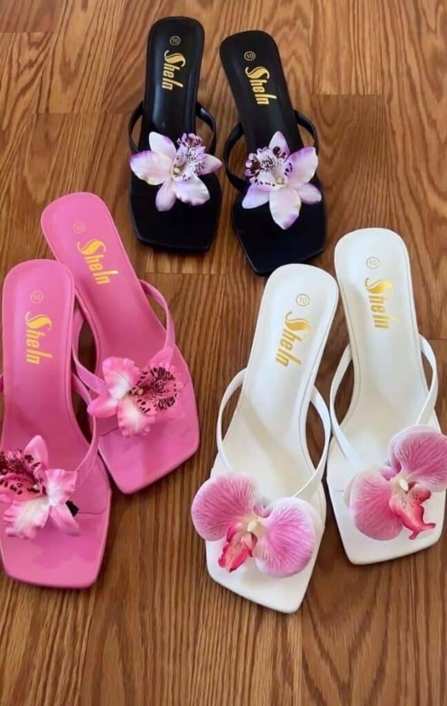 Stylish sandals with floral embellishments in black, pink, and white on hardwood floor.