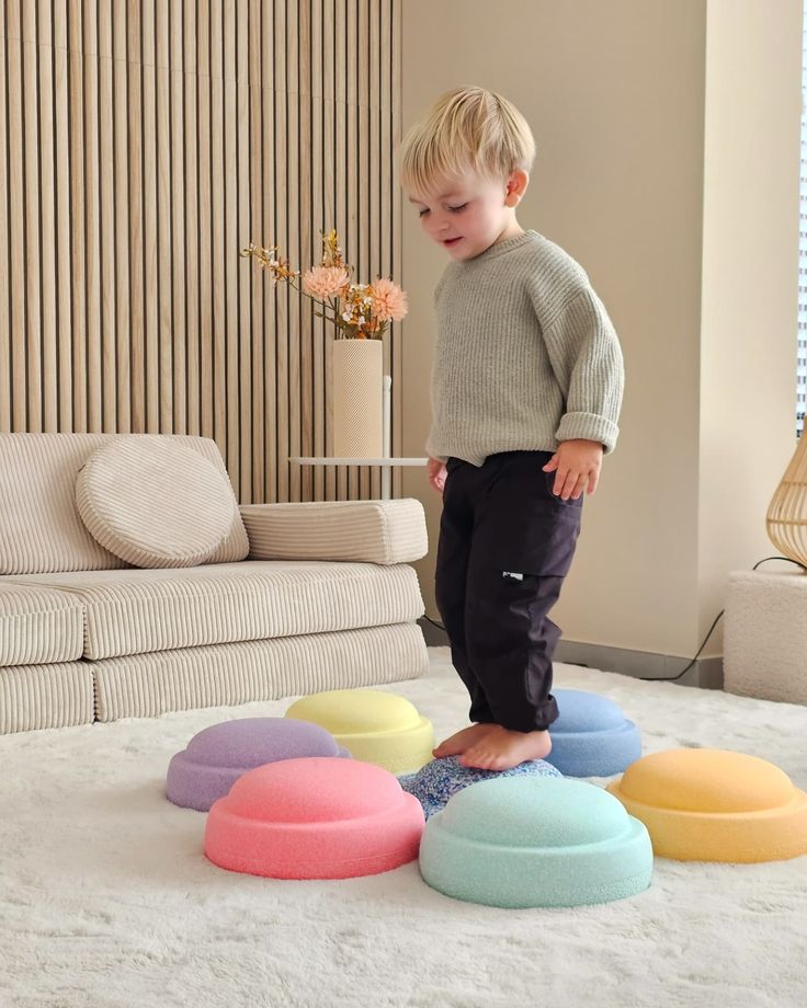 Toddler balancing on colorful foam stepping stones in a cozy living room.