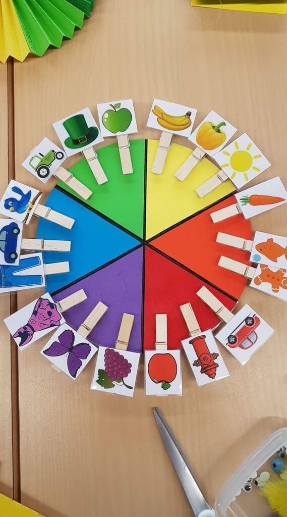 Color wheel game with matching objects attached with clothespins, ideal for teaching kids about colors and object association.