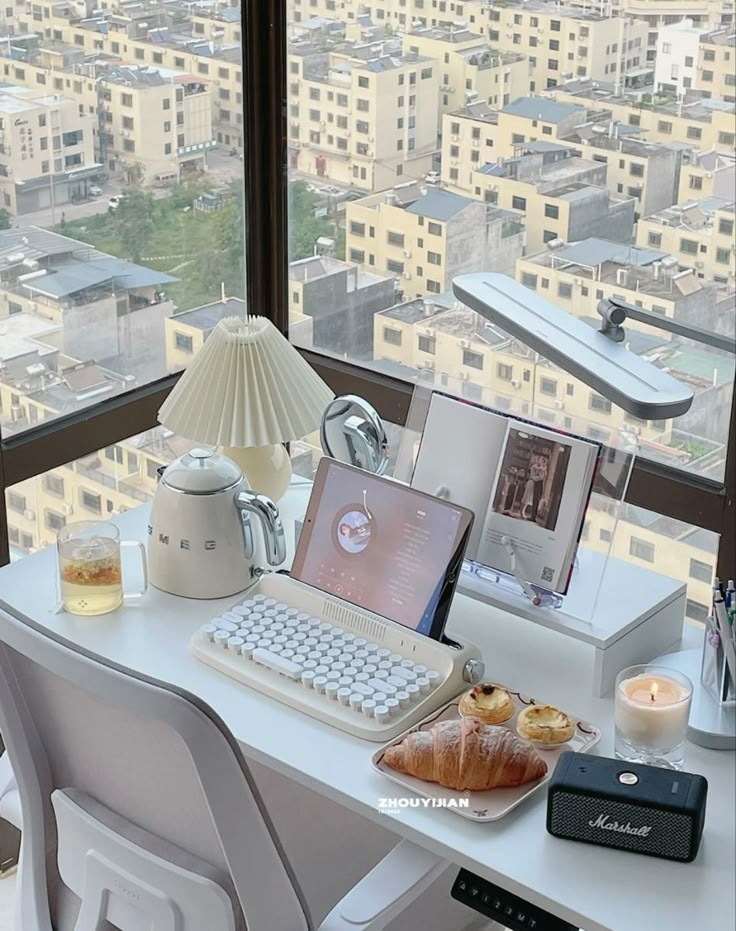 Cozy home office with tablet, keyboard, snacks, and tea, overlooking cityscape. Perfect work-from-home setup.