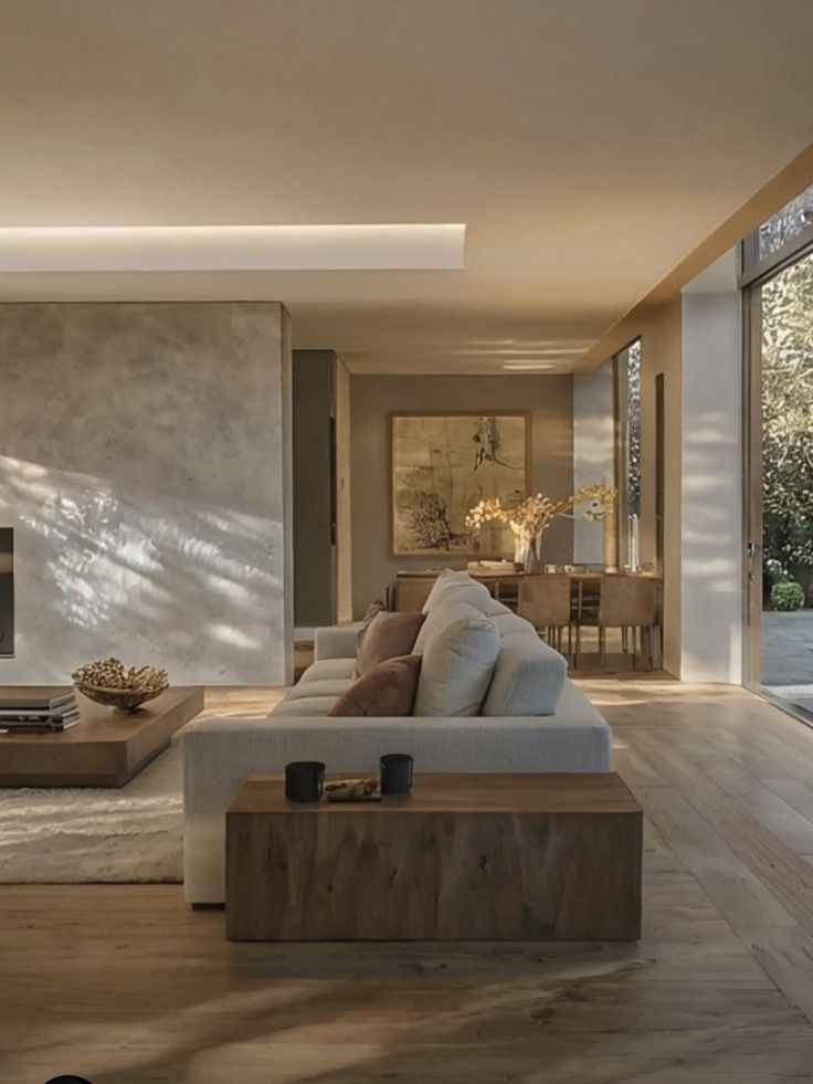 Modern living room with neutral decor, light wooden flooring, large windows, and a cozy sofa.
