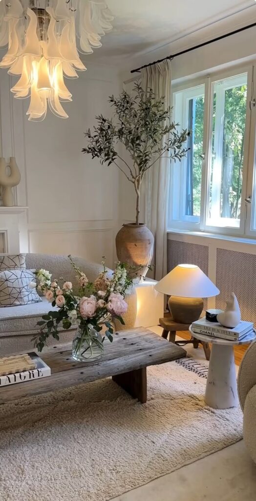 Minimalist living room with flowers, rustic wood table, modern decor, and large window for natural light.
