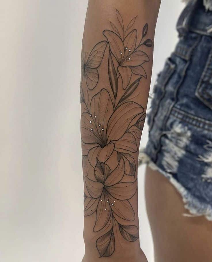 Floral arm tattoo with lilies and butterfly, detailed black ink design.
