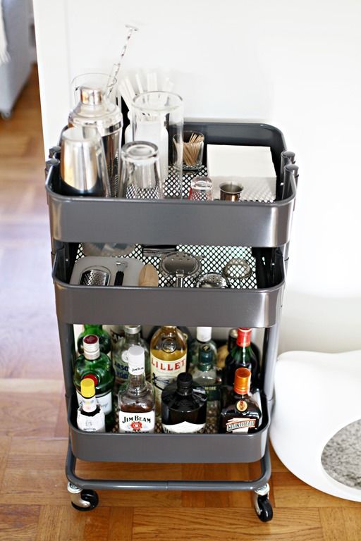 Mobile bar cart with bottles, glassware, and cocktail tools, ideal for home entertaining and stylish drink serving.