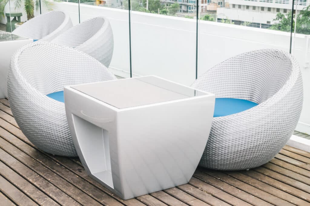 Empty chair and table with outdoor deck Modern outdoor patio furniture set with round white chairs and geometric table on a wooden deck. | Sky Rye Design Modern outdoor patio furniture set with round white chairs and geometric table on a wooden deck.