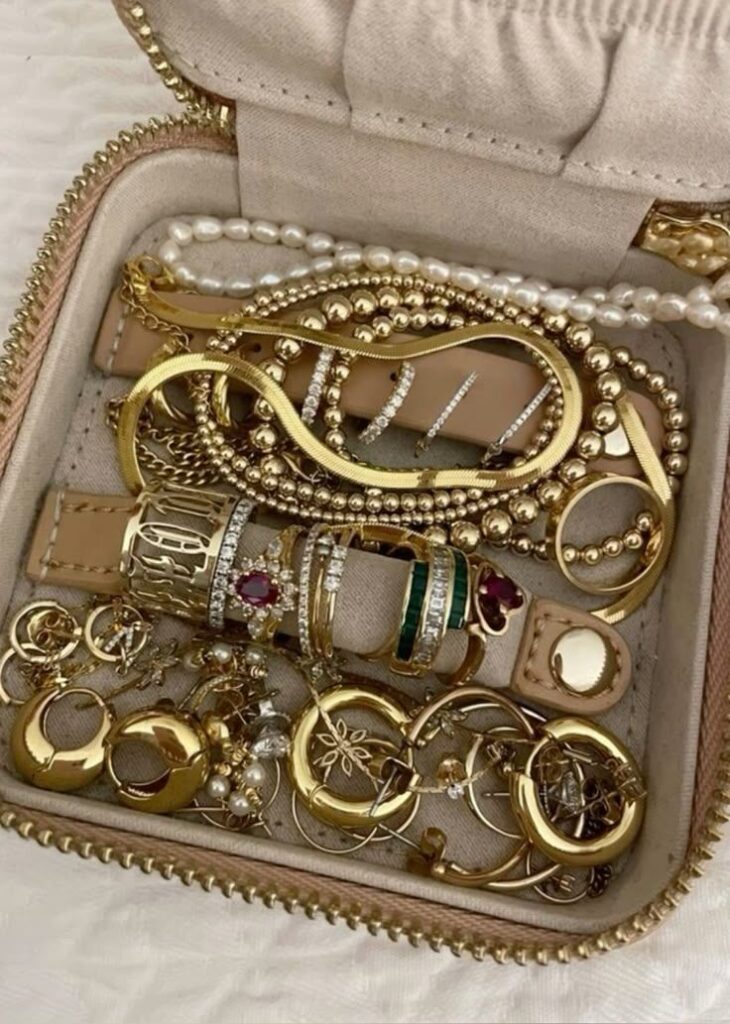 Elegant gold jewelry collection in a box, featuring rings, bracelets, and earrings, ideal for accessorizing occasions.