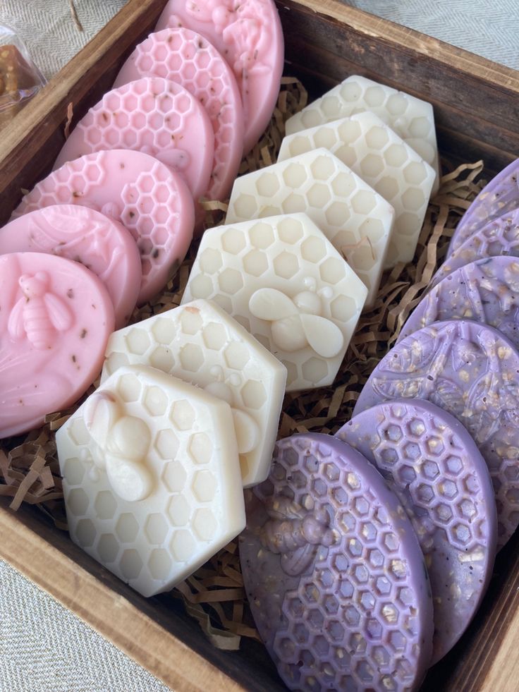 Handmade beeswax soap in pink, white, and purple with honeycomb design in a wooden box.