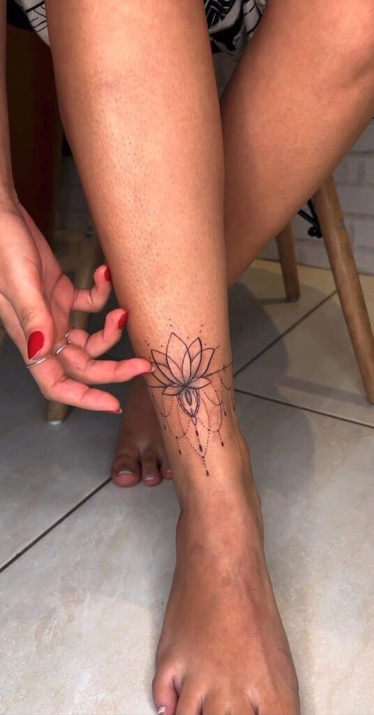 Minimalist floral ankle tattoo with dotwork details, displayed on a woman's leg.