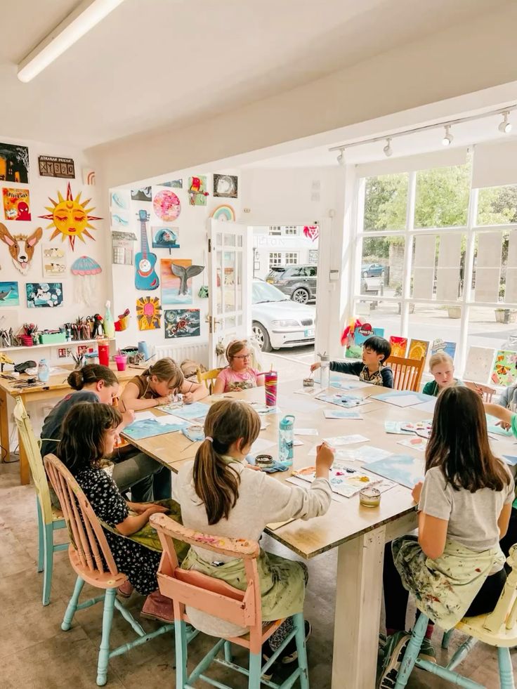 Children engaged in a colorful art class, painting and creating vibrant artwork in a sunlit studio.