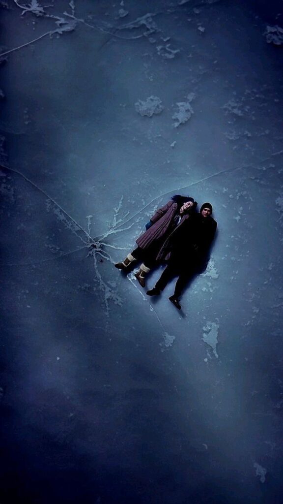 fbe395b509cc9d263027c2135dc2f494 Two people lying on a cracked ice surface, bundled up in winter clothing, under a serene night sky. | Sky Rye Design Two people lying on a cracked ice surface, bundled up in winter clothing, under a serene night sky.