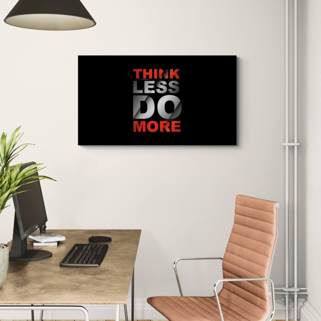Modern office with motivational Think Less Do More wall art, desk, computer, and plant for inspiration.