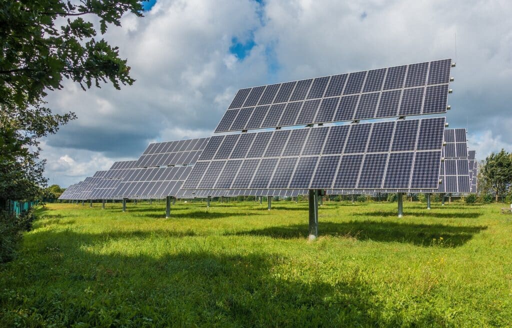 Solar panels in a sunny field, generating clean renewable energy under a blue sky with clouds.