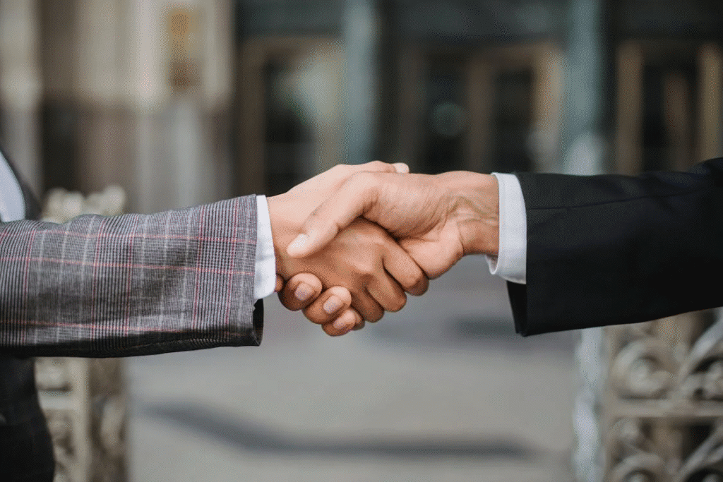 Two professionals shaking hands in agreement, wearing business suits, symbolizing partnership and cooperation.