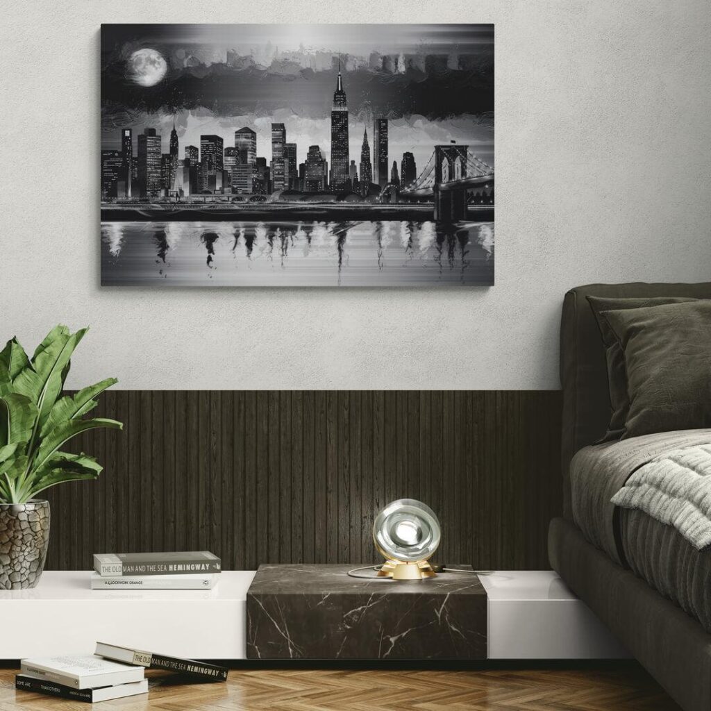 Modern living room with monochrome cityscape artwork, cozy couch, books, and a plant for a stylish interior.