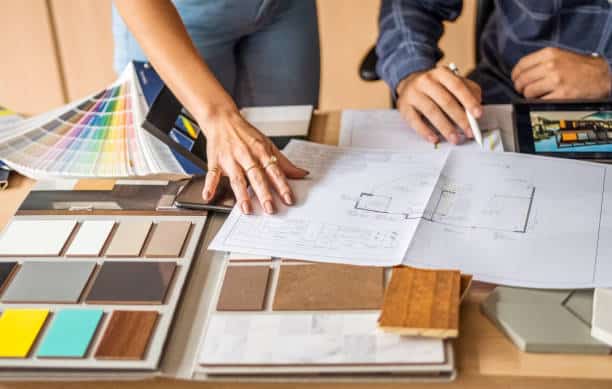 Interior designers reviewing color swatches and blueprints at a desk for a renovation project.