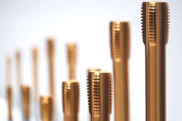 Close-up of golden drill taps in varying focus, showcasing precision tools for industrial applications and manufacturing.