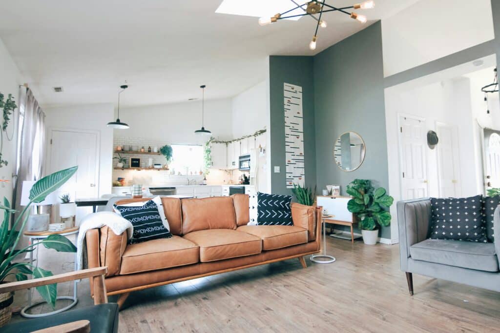 kara-eads-L7EwHkq1B2s-unsplash Modern living room with leather sofa, grey armchair, and stylish decor featuring plants and pendant lighting. | Sky Rye Design Modern living room with leather sofa, grey armchair, and stylish decor featuring plants and pendant lighting.