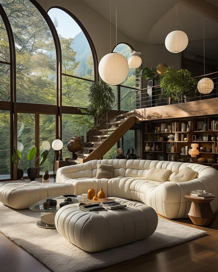 Modern living room with large windows, white sectional sofa, and hanging paper lanterns overlooking a lush forest view.