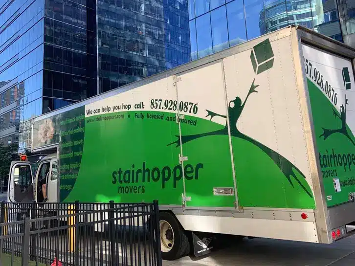 Moving truck for Stairhopper Movers parked in a city, displaying company logo and contact information.