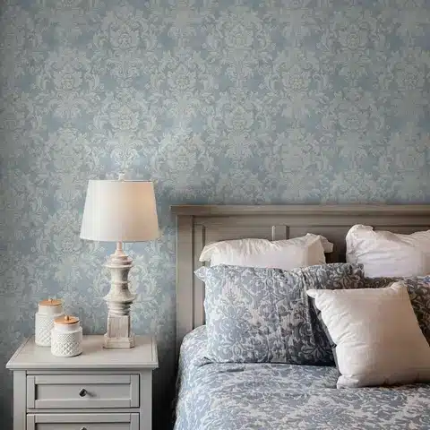 Elegant bedroom with floral wallpaper, cozy bed, decorative pillows, and a stylish bedside lamp on a white nightstand.