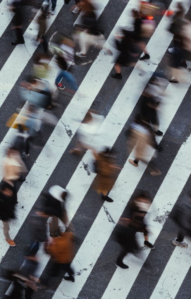 Aerial view of blurred pedestrians crossing a busy city crosswalk.