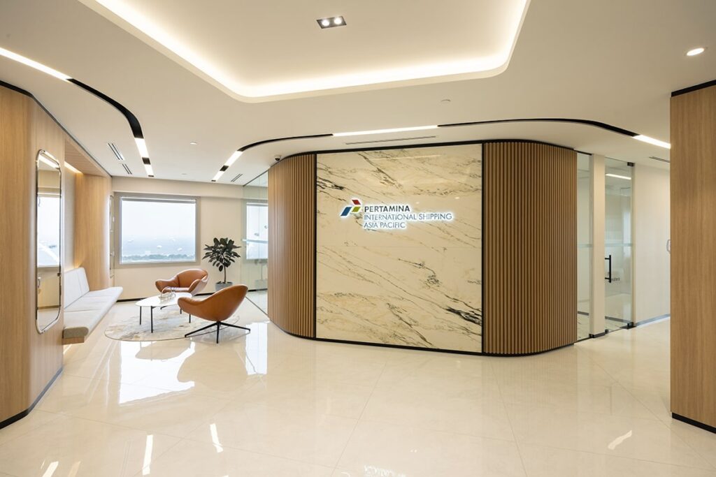 Modern office lobby with sleek design, marble walls, seating area, and Pertamina International signage.