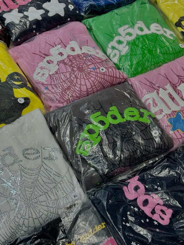 Colorful graphic t-shirts with various prints and sizes, packaged in clear plastic.