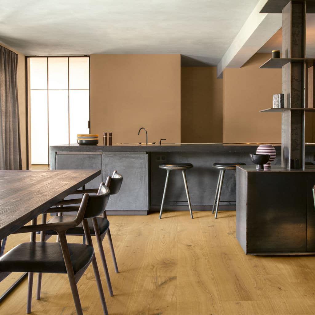 Modern kitchen with sleek gray cabinetry, wooden floors, large island, and minimalist dining area.