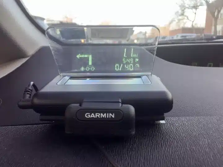 Garmin HUD navigation display on car dashboard showing turn directions and speed.