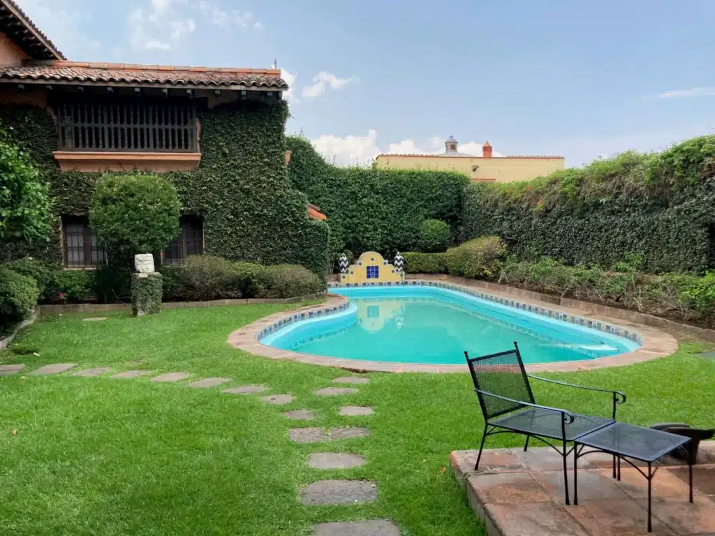 Charming backyard with ivy-covered walls, a kidney-shaped pool, and patio seating for relaxation.
