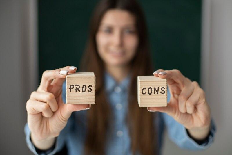 Person holding blocks with Pros and Cons text, symbolizing decision-making or comparison.