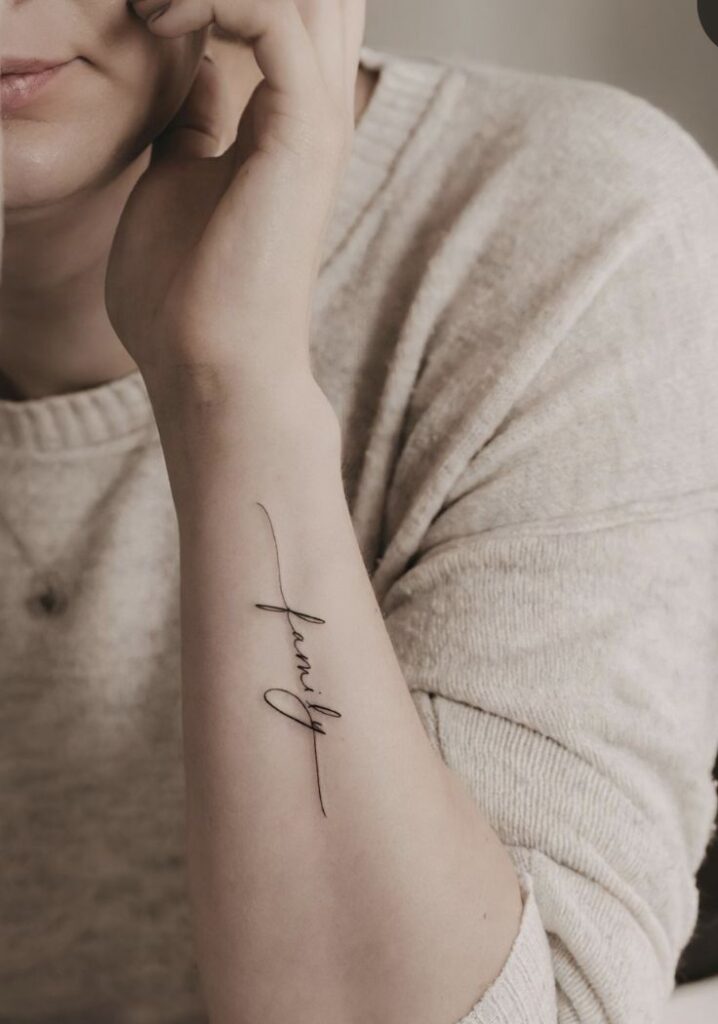 _ Elegant family script tattoo on forearm, cozy sweater background. | Sky Rye Design Elegant family script tattoo on forearm, cozy sweater background.