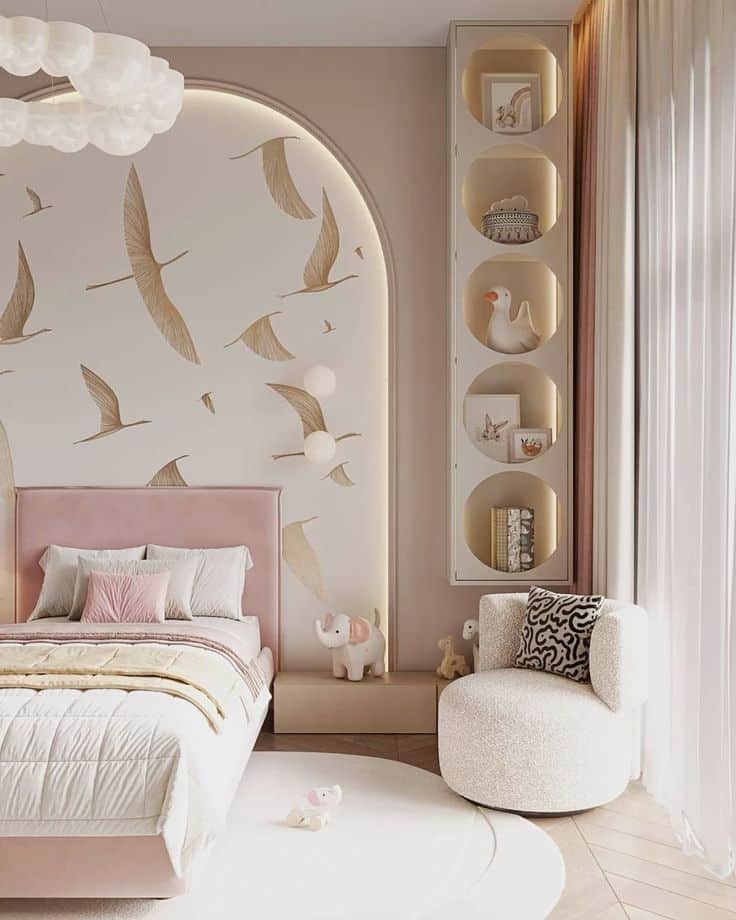 Chic children's bedroom with bird-themed wall, cozy pink bed, and plush white chair near window.