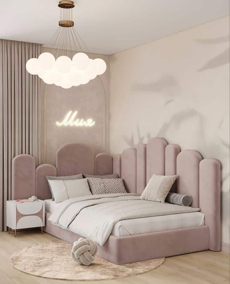 Elegant bedroom with pink upholstered bed, cloud chandelier, and stylish decor. Cozy and modern interior design.