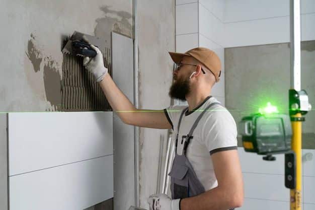 Construction worker applying tiles with a laser level guide.