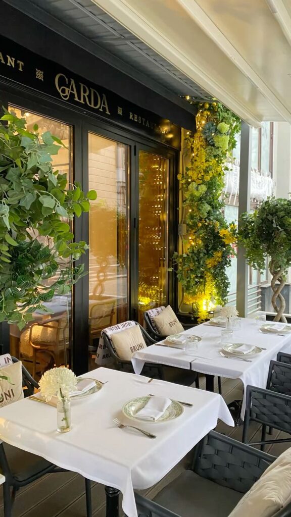 Elegant outdoor restaurant seating with white tablecloths, greenery, and cozy ambiance.