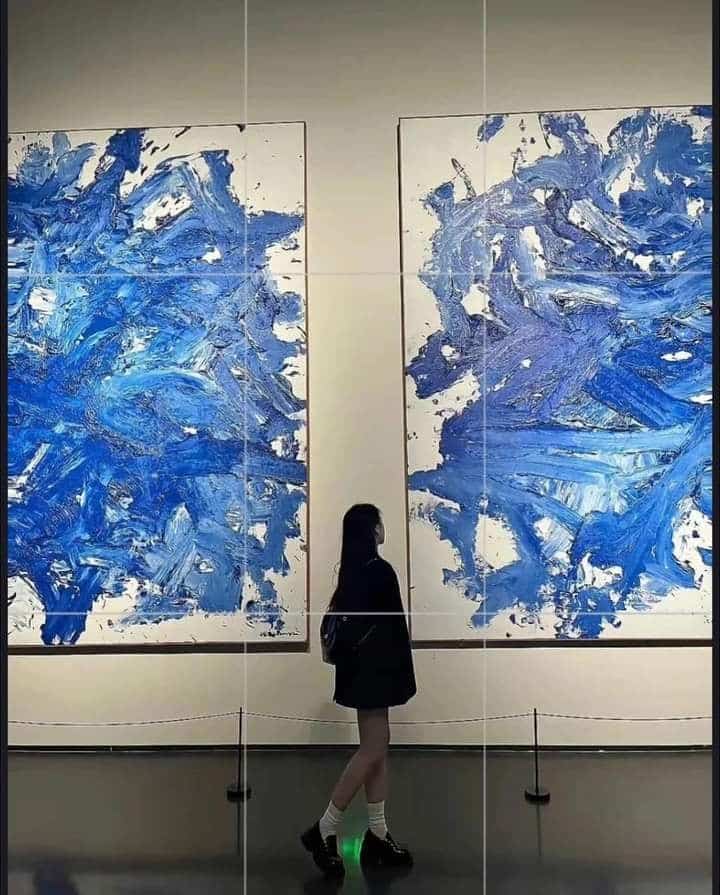 Person admiring abstract blue paintings in a gallery. Modern art exhibition, creativity, and inspiration concept.