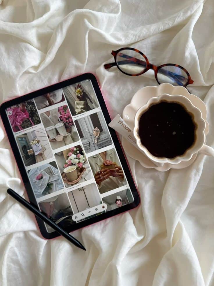 Tablet with floral images, coffee cup, and glasses on white fabric for aesthetic inspiration.