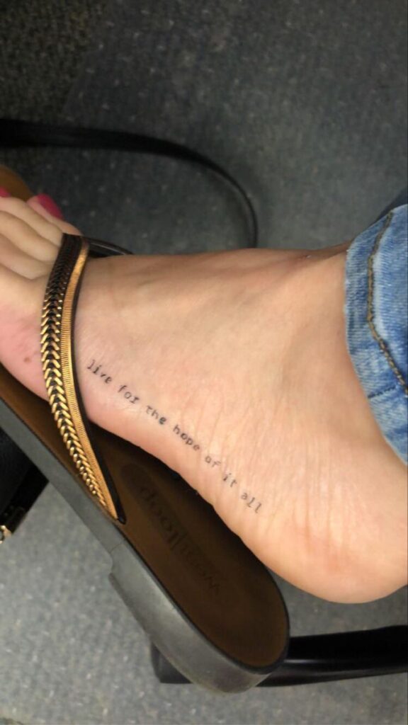 Foot with live for the hope of it all tattoo in sandals, close-up.