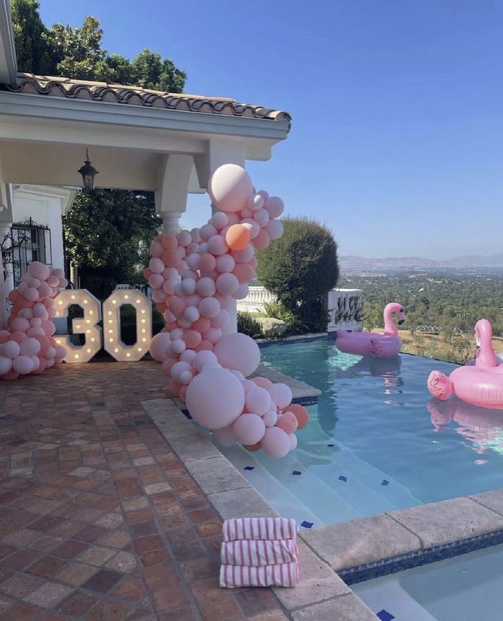 Poolside 30th birthday party with pink balloons and flamingo floats on a sunny day.
