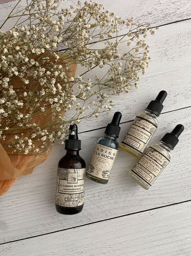 Natural skincare oils with dropper bottles and dried flowers on a white wooden surface. Elegant, organic products display.