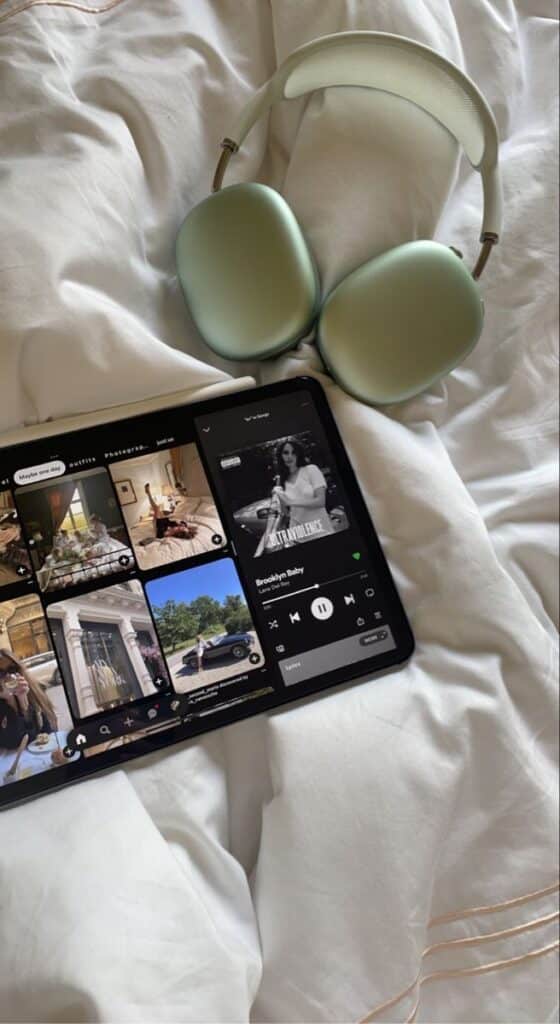 Tablet with headphones playing music on a bed, featuring a photo app and music streaming interface.
