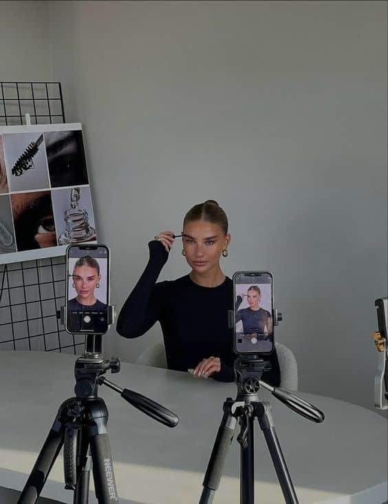 Social media influencer recording beauty tutorial with smartphones on tripods.