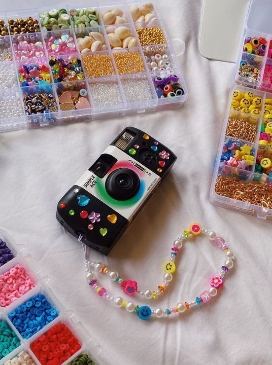 Colorful beads and a decorated camera with retro vibe on white background.