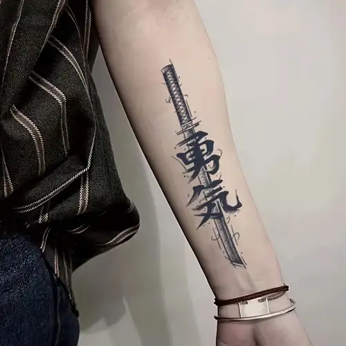 134dda71-5fd2-4cff-86ed-201e8a03388a Tattoo of Japanese calligraphy on a person's forearm, featuring a vertical sword design. | Sky Rye Design Tattoo of Japanese calligraphy on a person's forearm, featuring a vertical sword design.