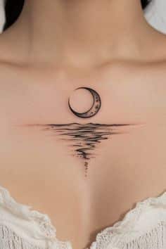 Crescent moon tattoo on woman's chest with serene water reflection design, wearing a white lace top.
