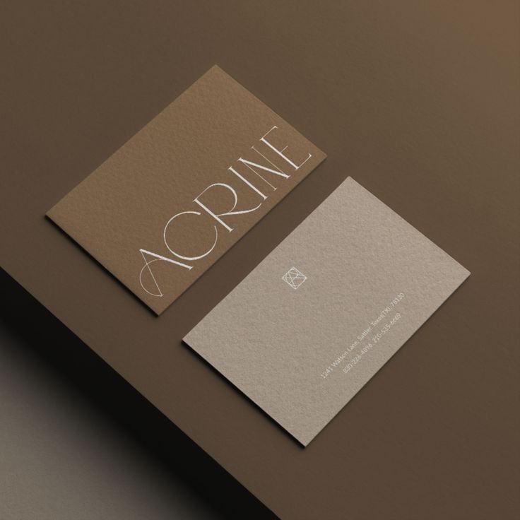 Elegant brown and beige business cards on a brown surface, featuring modern typography and design.
